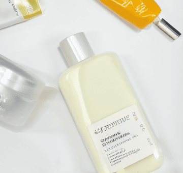 A bright close crop of a lotion bottle and skincare tube on a clean white editorial surface.