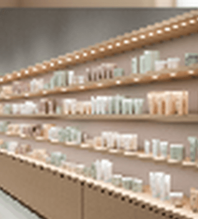 A calm retail shelf crop showing neatly merchandised Korean skincare products on warm illuminated shelving.
