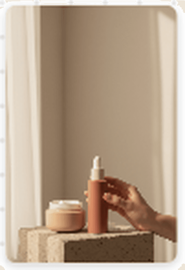 A warm editorial still life of Korean skincare with a serum bottle, cream jar, and hand in morning window light.